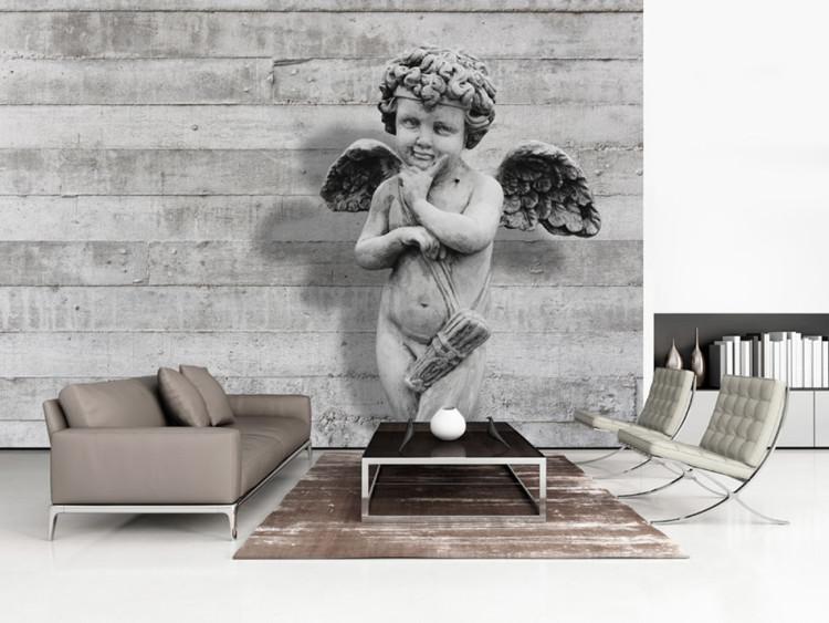 Fototapeta Uroczy kamienny cherubinek - rzeźba anioła na tle w betonowe pasy